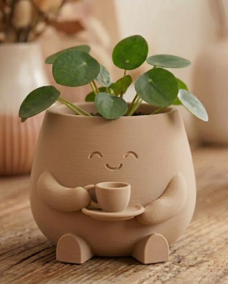 Beiger Blumentopf mit Tasse und grüner Zimmerpflanze als gemütliche Wohndekoration auf Holztisch