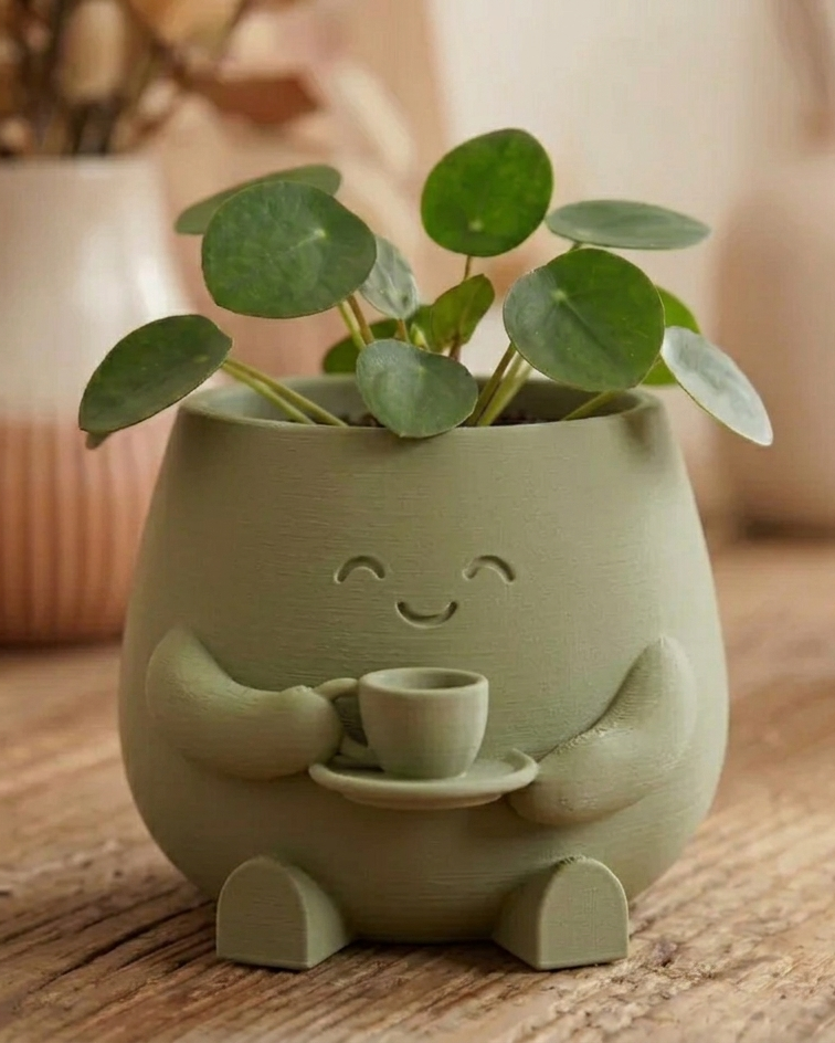 Grüner Blumentopf mit Tasse und grüner Zimmerpflanze als gemütliche Wohndekoration auf Holztisch