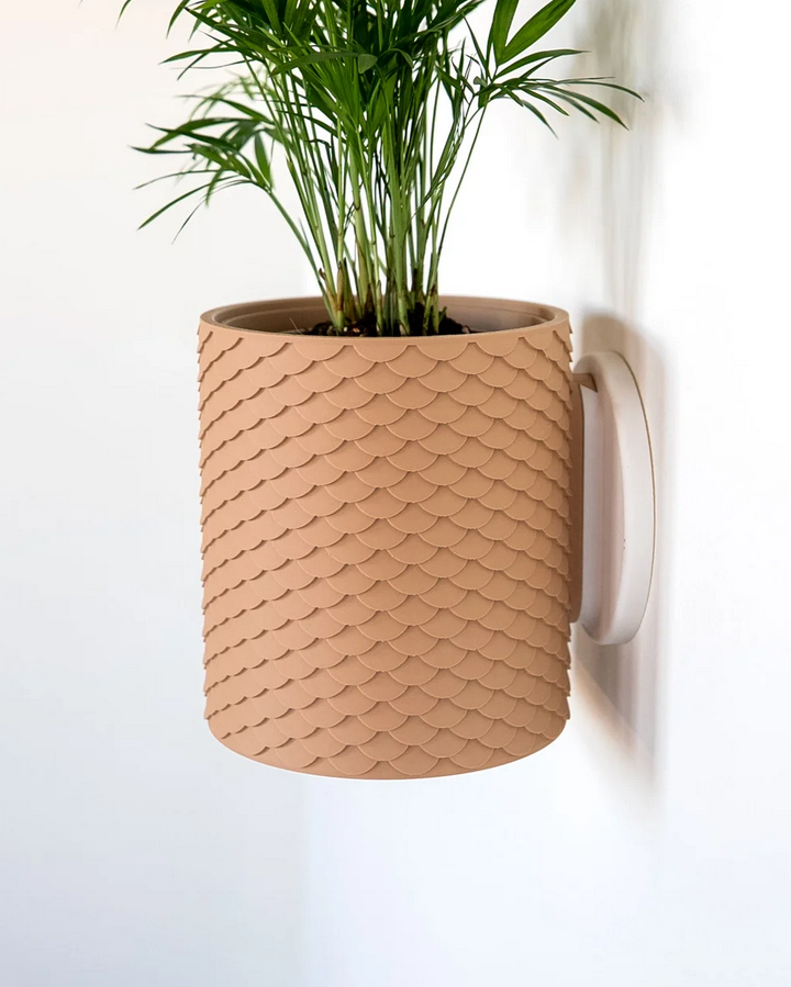Beiger Wandpflanztopf mit schuppenförmiger Struktur und grüner Zimmerpflanze