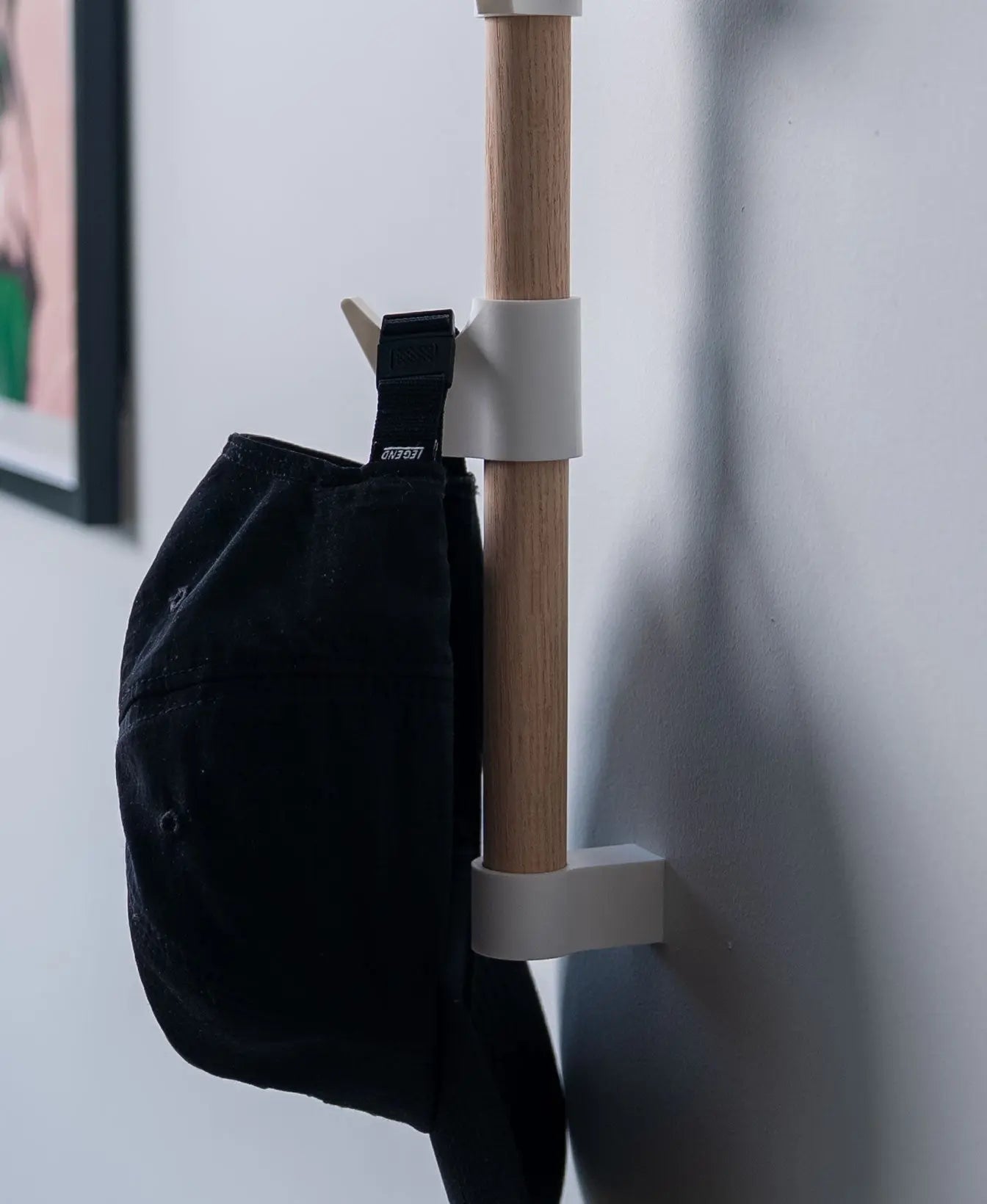 Schwarze Mütze hängt an einem weissen Haken des Evoliv Horizontal Rail Systems an einer Holzschiene.
