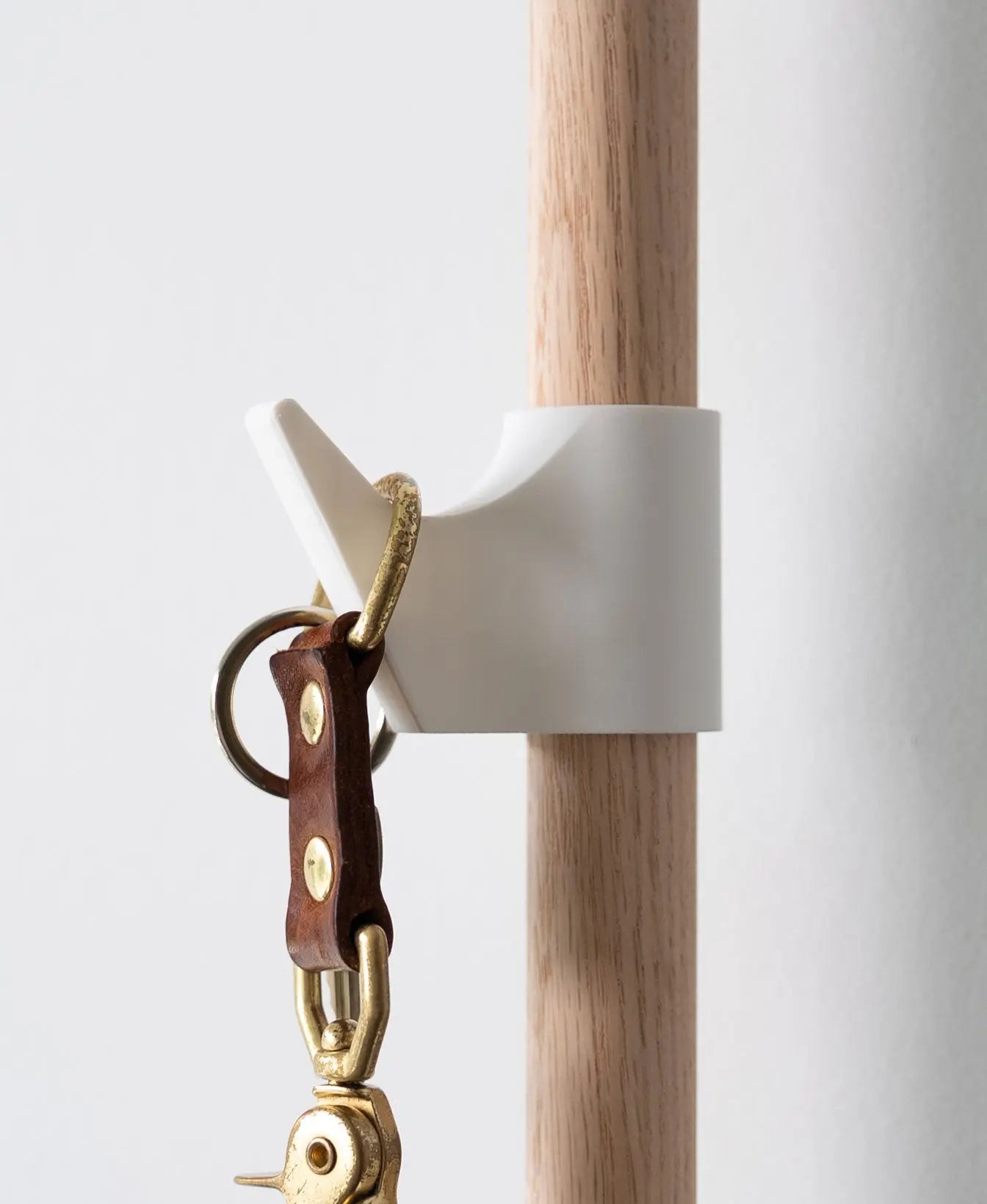 Weisser Kleiderhaken am Evoliv Horizontal Rail System mit Holzschiene zum Aufhängen von Schlüsseln oder Accessoires.