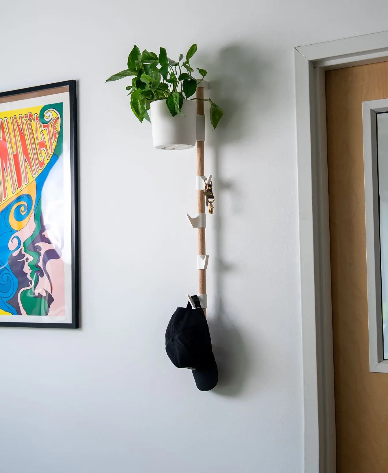 Evoliv Horizontal Rail System mit Blumentopf und Haken an Holzschiene zur Aufbewahrung von Schlüsseln und Mütze an der Wand.